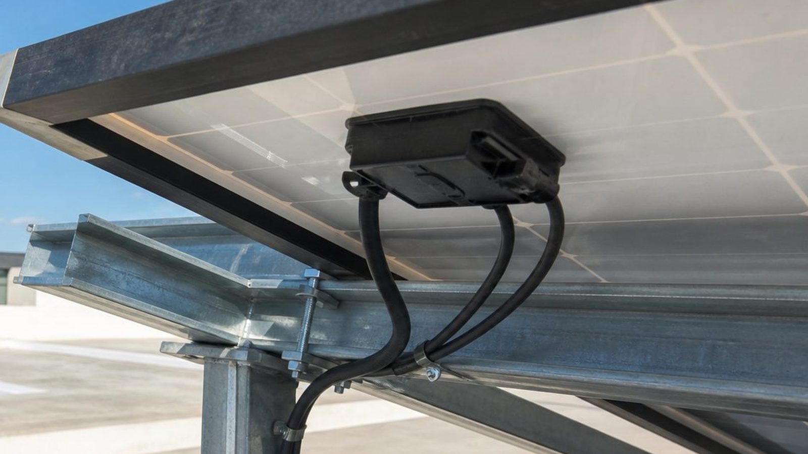 Solar module strings on a flat rooftop with DC cables and connectors routed along the mounting rails